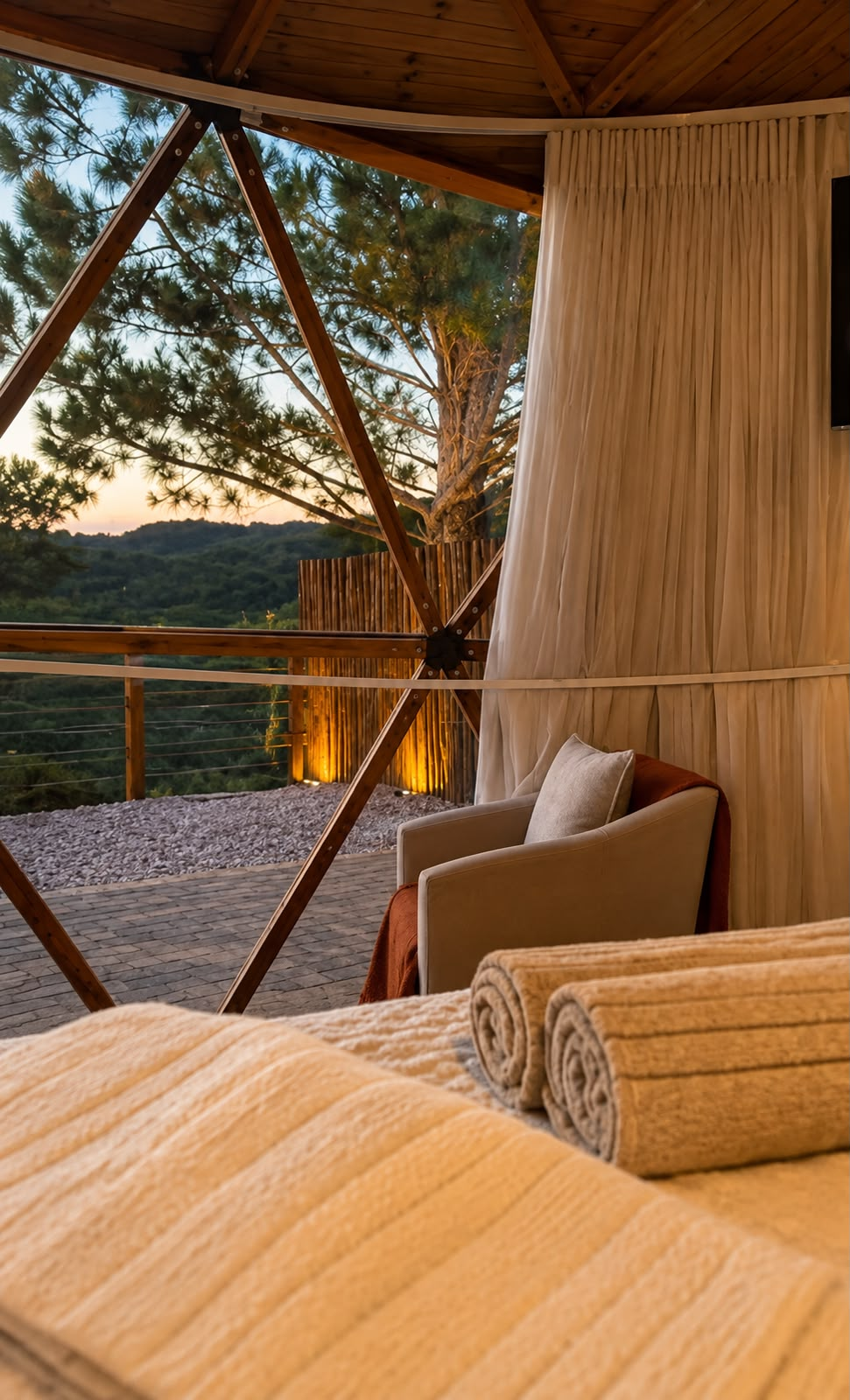Lounge do domo ao entardecer com poltronas e vista para a mata