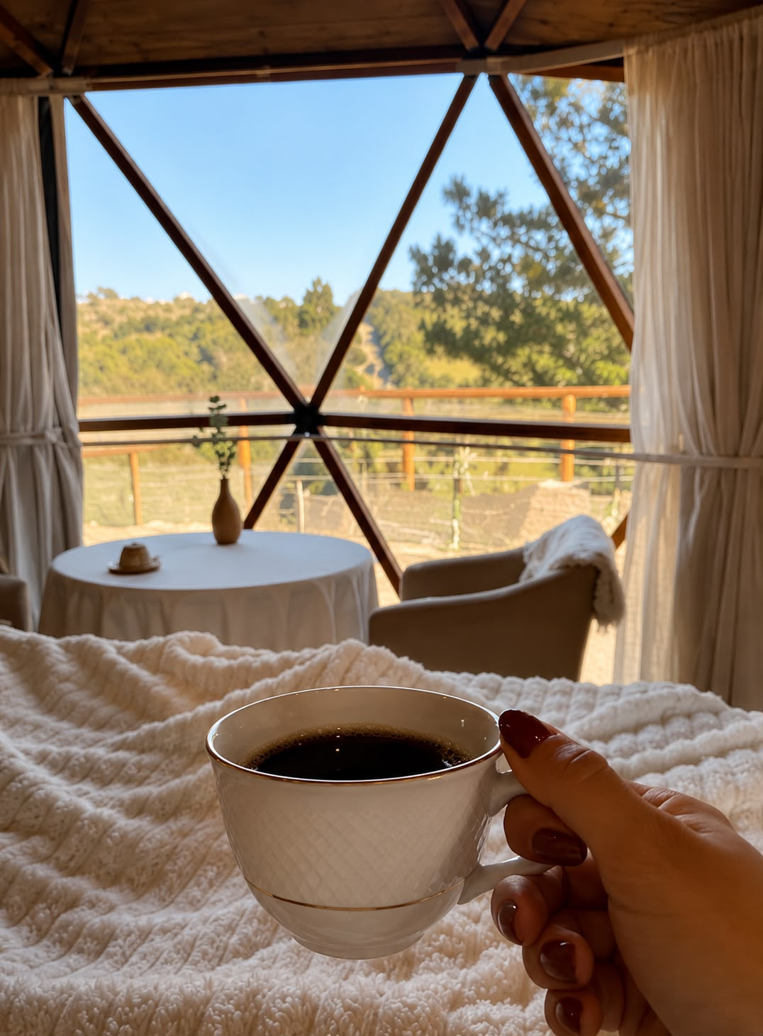 Café servido na cama com vista para as montanhas pela janela do domo